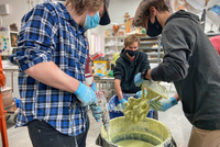 Students prepping for the Iron Pour by dipping sprued wax molds into a slurry, which then hardens into a ceramic shell. 