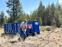 BLM Park Ranger Charles Lindberg heaves a load into the dumpster