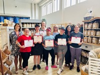 Several course participants pose with their certificates of completion alongside representatives from Cougar Tracks and Grace Kitchen.