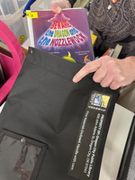 Staff at the Oregon City Public Library stuffs a Library By Mail bag with a hold item requested by a homebound patron. 